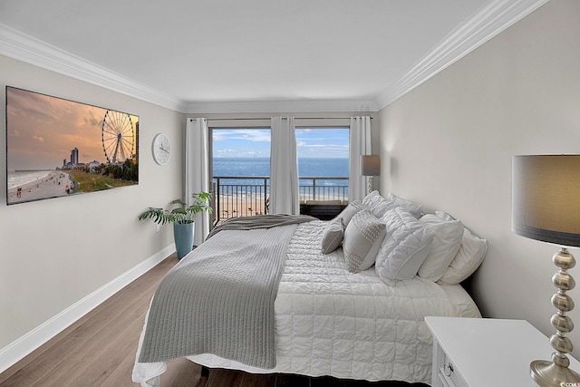 bedroom featuring ornamental molding, wood finished floors, access to exterior, baseboards, and a water view