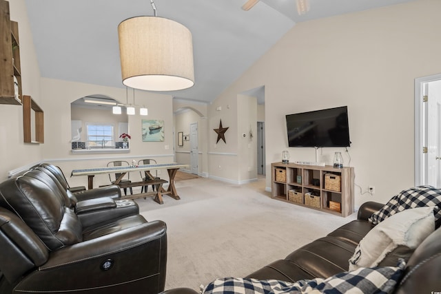 living area featuring arched walkways, light colored carpet, baseboards, and high vaulted ceiling