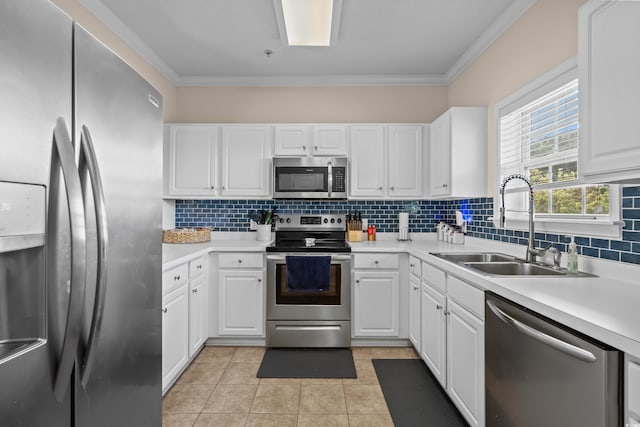 kitchen featuring appliances with stainless steel finishes, a sink, white cabinetry, backsplash, and crown molding