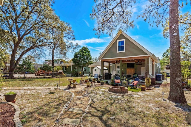 rear view of house featuring an outdoor fire pit, fence, and ceiling fan