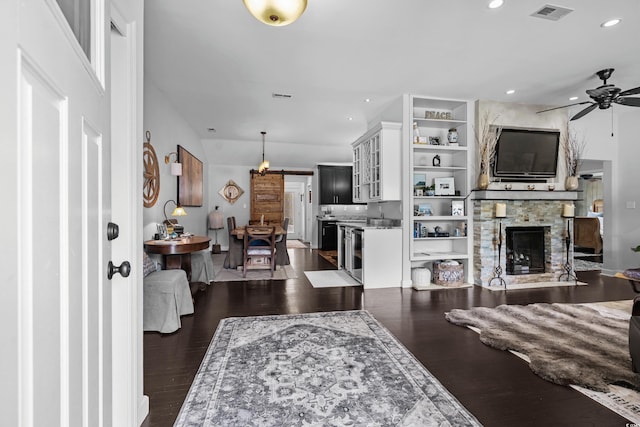 710 Yucca Ave, Myrtle Beach, SC 29577 - living room with ceiling fan, a barn door, a stone fireplace, recessed lighting, and dark wood-style flooring