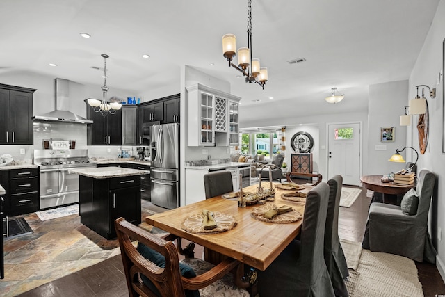 dining space with a chandelier, recessed lighting, and dark stone finish flooring