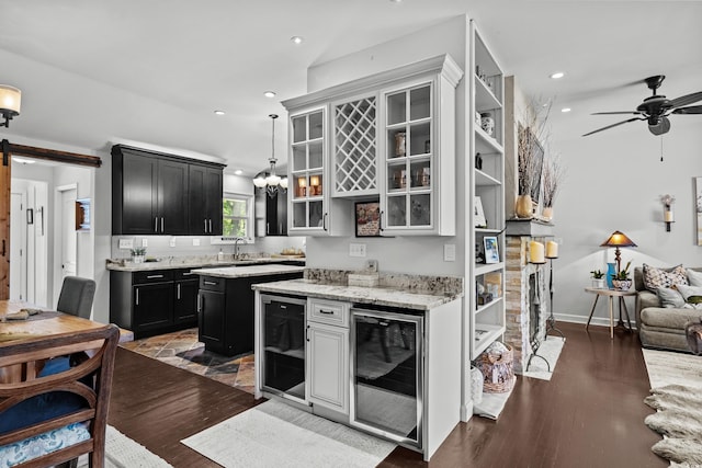 kitchen with wine cooler, dark cabinets, a barn door, glass insert cabinets, and recessed lighting
