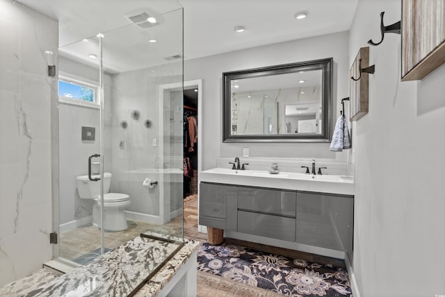 bathroom with a shower stall, double vanity, toilet, and recessed lighting