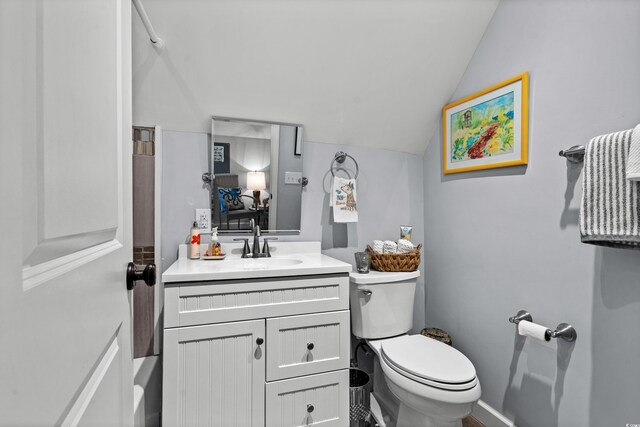 bathroom featuring vaulted ceiling, toilet, vanity, and baseboards