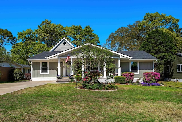 view of front of house with board and batten siding, a front yard, and concrete driveway