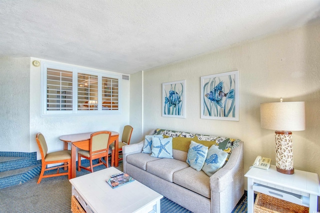 living area featuring a textured ceiling, visible vents, and a textured wall
