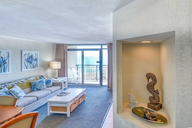 living room with a textured ceiling, a textured wall, floor to ceiling windows, and tile patterned flooring