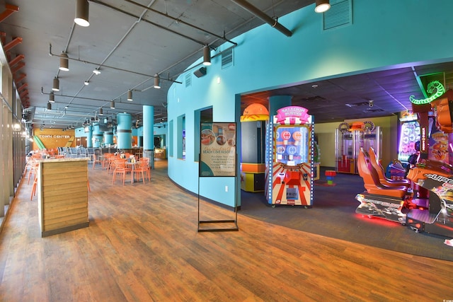 playroom with visible vents, a towering ceiling, and wood finished floors