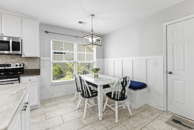 356 Whipple Run Loop, Myrtle Beach, SC 29588 - dining area with a chandelier, a wainscoted wall, and a decorative wall