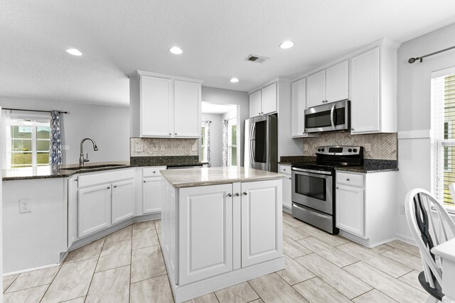356 Whipple Run Loop, Myrtle Beach, SC 29588 - kitchen featuring stainless steel appliances, a peninsula, tasteful backsplash, white cabinetry, and dark stone counters