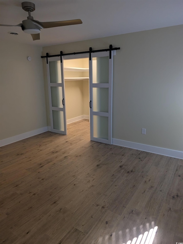 880 Briarwood Dr, Myrtle Beach, SC 29572 - unfurnished bedroom with a barn door, wood finished floors, a walk in closet, and a closet