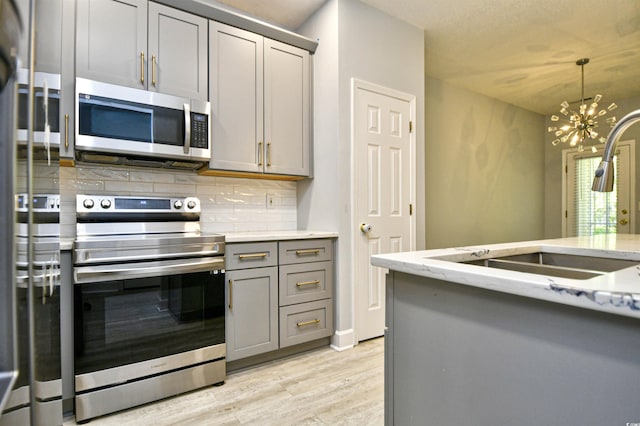 121 Olde Towne Way Unit 2, Myrtle Beach, SC 29588 - kitchen with light wood finished floors, a chandelier, gray cabinets, stainless steel appliances, and tasteful backsplash