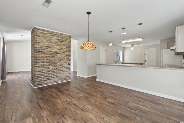 unfurnished living room with dark wood-type flooring, visible vents, ceiling fan, and a sink