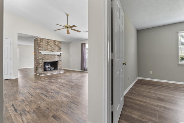 unfurnished living room with wood finished floors, ceiling fan, baseboards, and vaulted ceiling