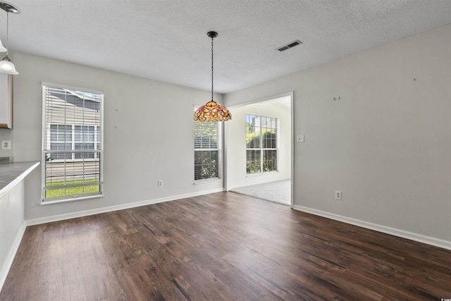 unfurnished dining area with visible vents, dark wood-style flooring, baseboards, and a healthy amount of sunlight