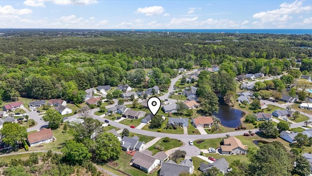 aerial view featuring a wooded view, a residential view, and a water view