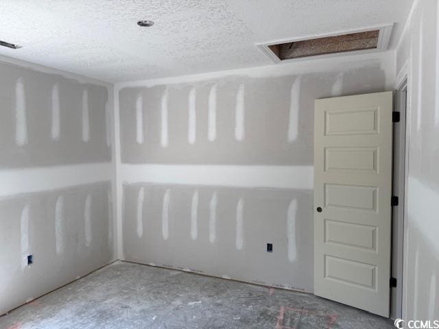 unfurnished room with visible vents, attic access, and a textured ceiling