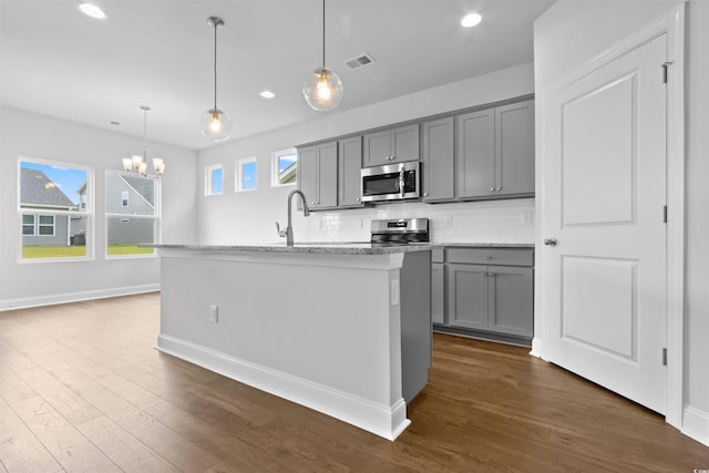kitchen featuring appliances with stainless steel finishes, gray cabinets, tasteful backsplash, dark wood-type flooring, and recessed lighting