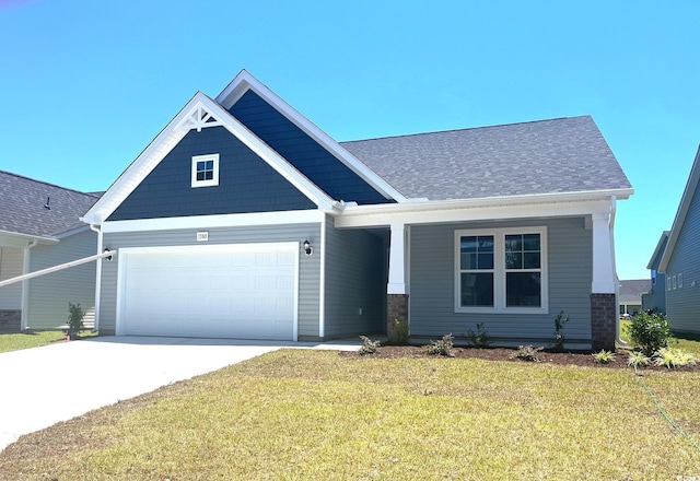 craftsman-style home featuring an attached garage, concrete driveway, a front lawn, and roof with shingles