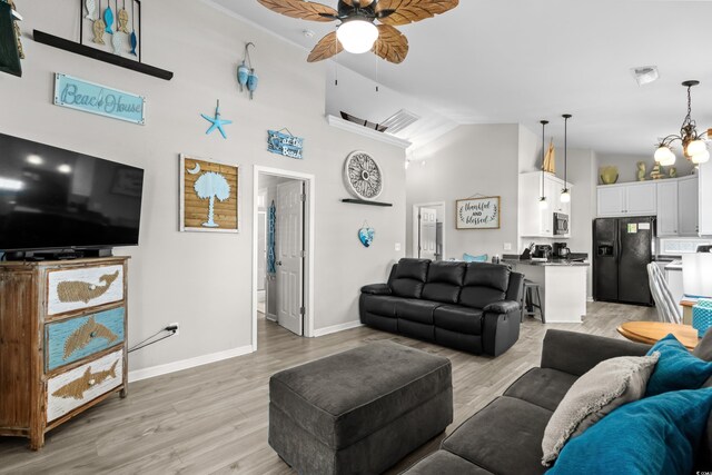 6001-8050 S Kings Hwy, Myrtle Beach, SC 29575 - living area with light wood-style flooring, baseboards, visible vents, ceiling fan with notable chandelier, and high vaulted ceiling