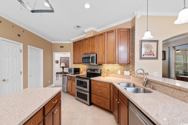 kitchen featuring ornamental molding, visible vents, appliances with stainless steel finishes, a sink, and brown cabinets