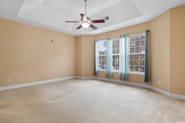 spare room featuring a raised ceiling, visible vents, ceiling fan, and carpet floors