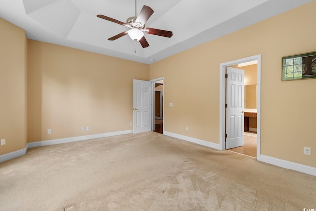 unfurnished bedroom with a tray ceiling, baseboards, carpet flooring, and ensuite bathroom