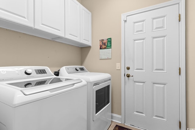 washroom featuring cabinet space, washing machine and clothes dryer, and baseboards