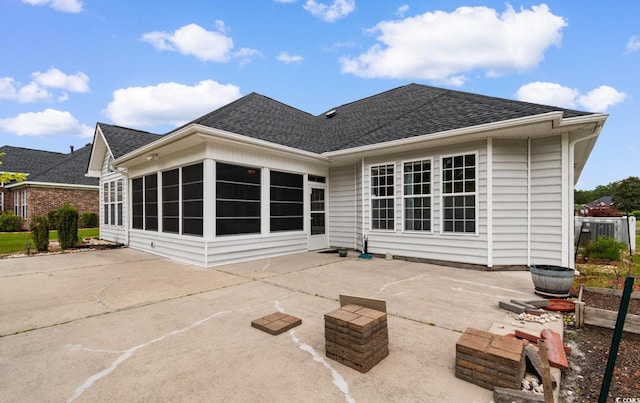 rear view of house featuring a sunroom, a shingled roof, and a patio area