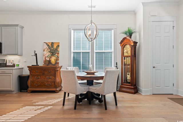 dining room with an inviting chandelier, crown molding, light wood finished floors, and baseboards