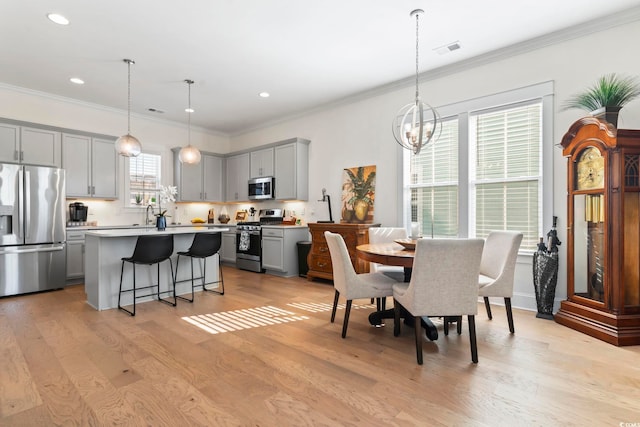 dining room featuring crown molding, visible vents, and light wood-style flooring