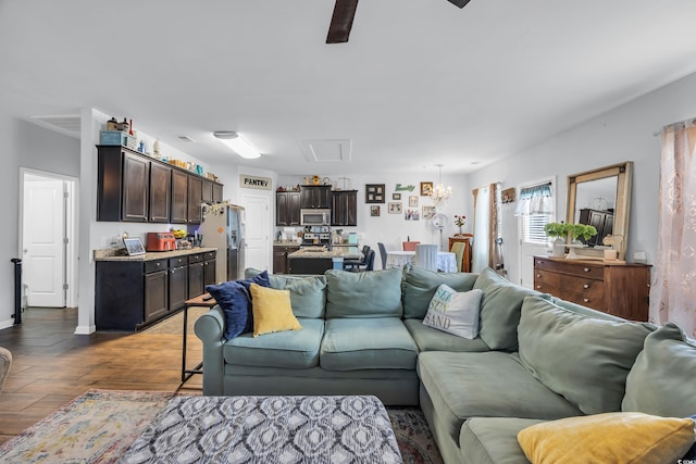 living area with ceiling fan with notable chandelier and wood finished floors