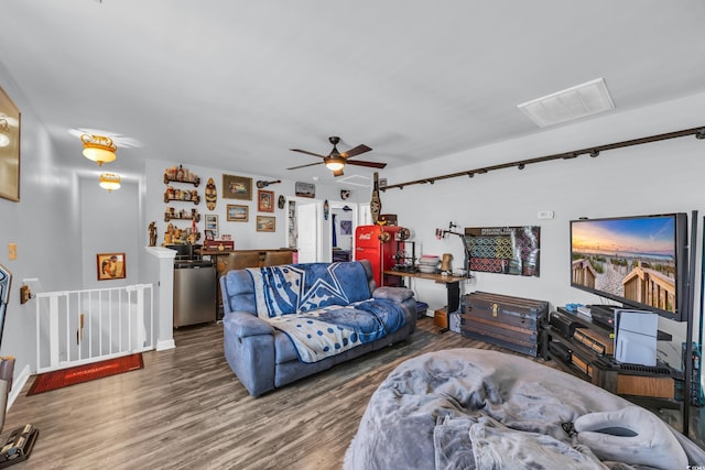 living room with wood finished floors, visible vents, and a ceiling fan