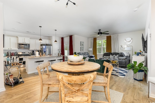 dining area with a ceiling fan and light wood-style floors