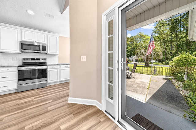 1516 Saint George Ln, Myrtle Beach, SC 29588 - kitchen with decorative backsplash, visible vents, appliances with stainless steel finishes, light wood-style floors, and white cabinetry