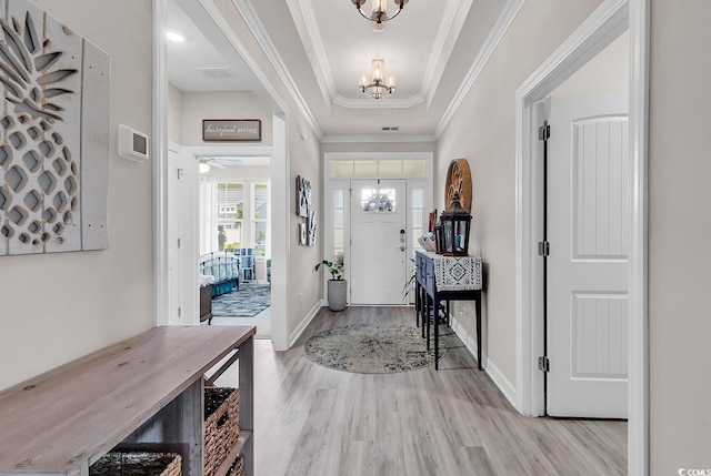 foyer entrance with a tray ceiling, light wood-type flooring, baseboards, and ornamental molding