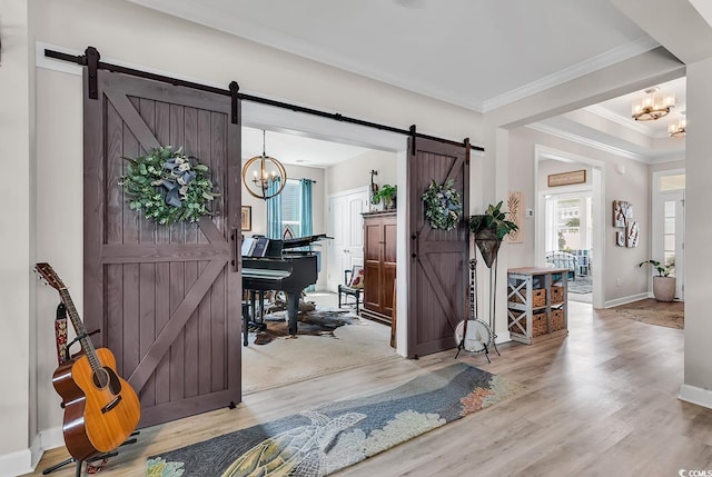 foyer entrance featuring a barn door, crown molding, wood finished floors, and a chandelier