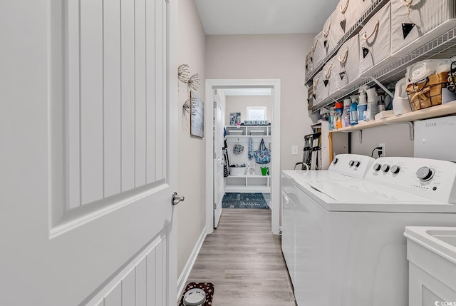 clothes washing area featuring a sink, separate washer and dryer, light wood finished floors, baseboards, and laundry area