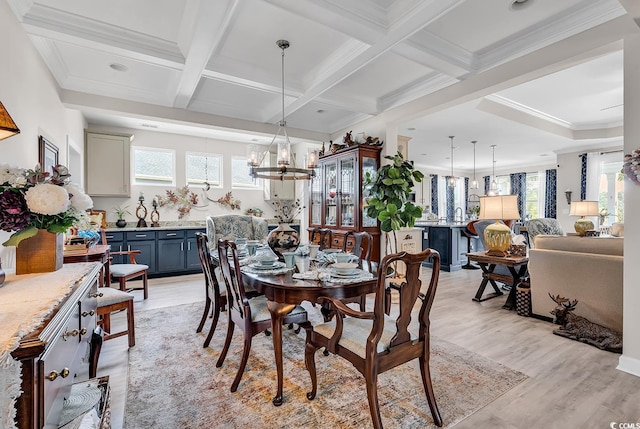 dining room featuring ornamental molding, a notable chandelier, light wood-style floors, and beamed ceiling
