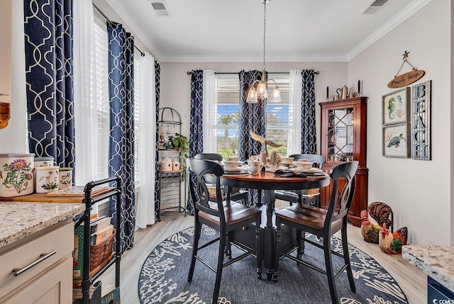 dining space with a chandelier, crown molding, visible vents, and light wood finished floors
