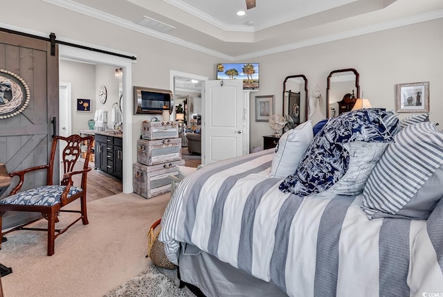 bedroom featuring a barn door, visible vents, light colored carpet, ornamental molding, and a raised ceiling