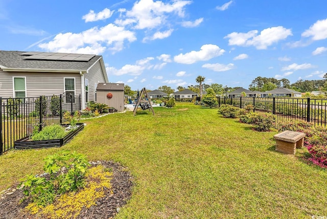 view of yard featuring a vegetable garden, a fenced backyard, an outbuilding, a residential view, and a storage unit