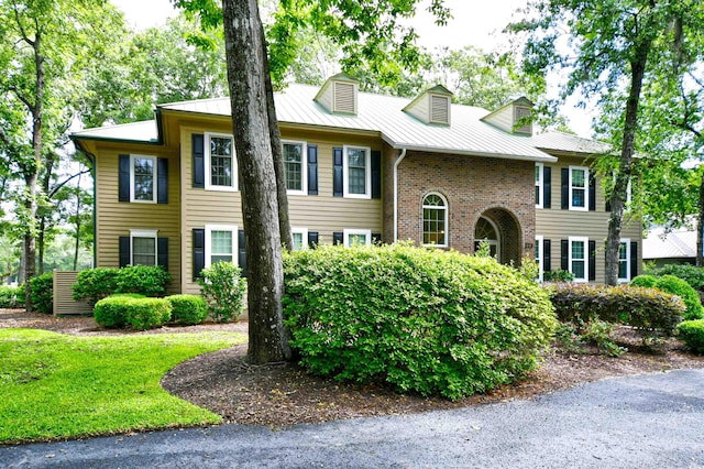 view of front of home with brick siding, metal roof, and a standing seam roof