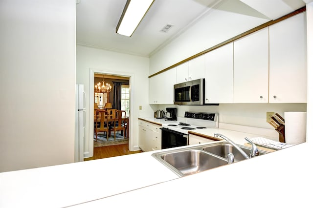 kitchen featuring stainless steel microwave, range with electric stovetop, freestanding refrigerator, a chandelier, and light countertops