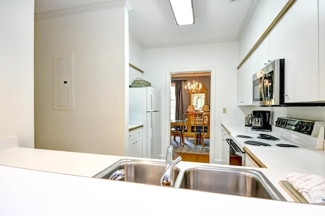 kitchen featuring white appliances, ornamental molding, a chandelier, electric panel, and light countertops