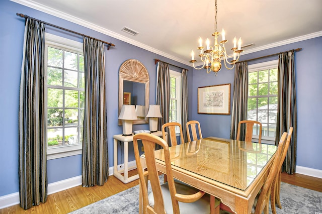dining space with a chandelier, light wood-style flooring, plenty of natural light, and ornamental molding