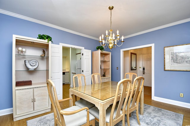dining space with a chandelier, ornamental molding, baseboards, and wood finished floors
