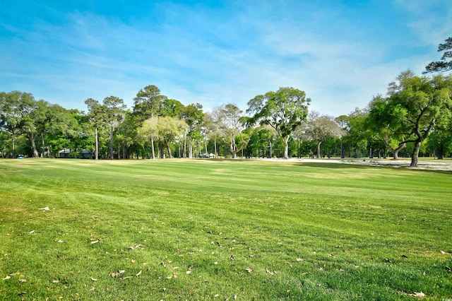 view of community featuring view of wooded area, a lawn, and view of golf course