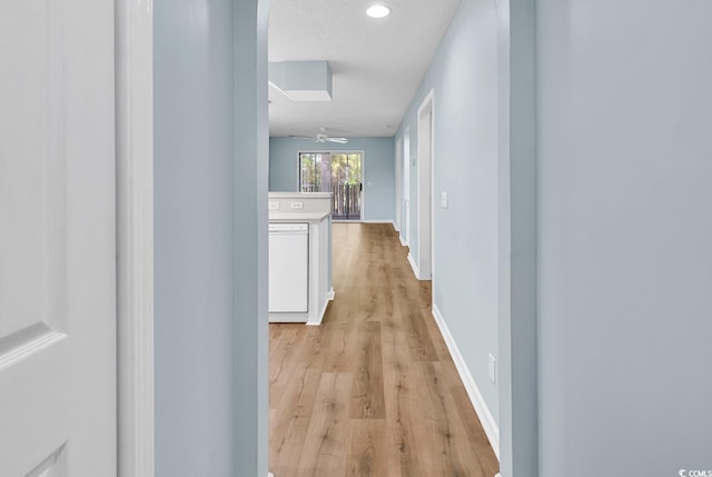 hallway featuring light wood finished floors, baseboards, and recessed lighting